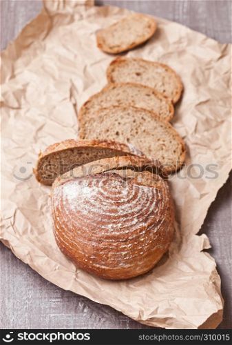 Freshly baked bread loaf with pieces on white wooden board