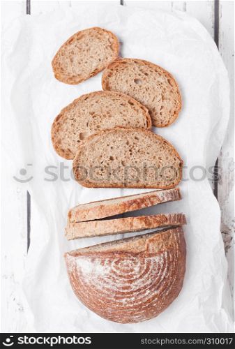 Freshly baked bread loaf with pieces on white wooden board