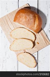 Freshly baked bread loaf with pieces on wood boardon white wooden board