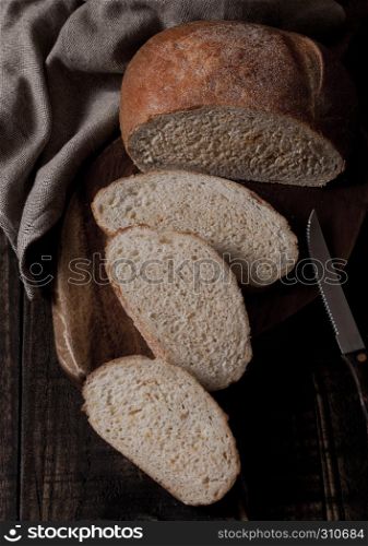 Freshly baked bread loaf with pieces on wood boardon wooden board with kitchen towel