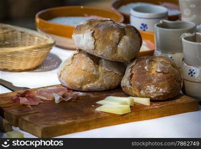 Freshly baked bread on cutting board with cheeses and cold cuts