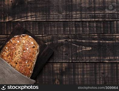 Freshly baked bread with oats and kitchen towel on wooden board background