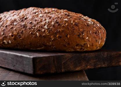 Freshly baked bread with oats on wooden board background