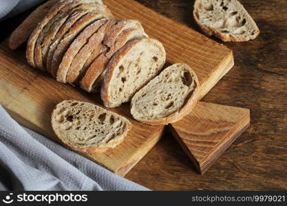 Freshly baked ciabatta bread sliced on wooden cutting board with knife .. Freshly baked ciabatta bread sliced on wooden cutting board with knife