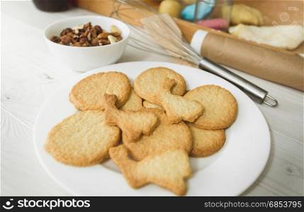 Freshly baked cookies lying on white dish at kitchen