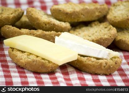 freshly baked crisp bread rolls with brie cheese over white and red cloth fabric