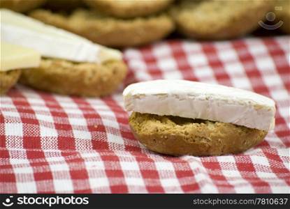 freshly baked crisp bread rolls with brie cheese over white and red cloth fabric