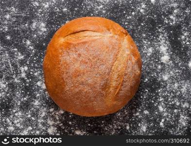Freshly baked gluten free organic bread with flour on black background