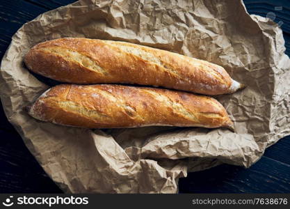 Freshly baked homemade baguette bread on dark wooden table