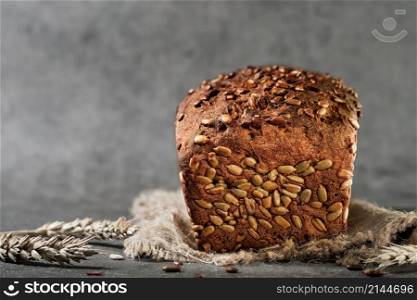 Freshly baked wheat and rye bread with seeds on burlap, close-up with selective focus. Fermented healthy bread, gray background with space for text