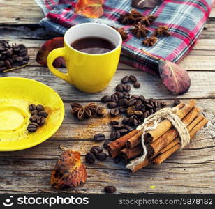 Freshly brewed coffee in the fall. Yellow cup of black coffee on background with autumn leaves