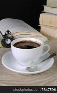 freshly brewed cup of fragrant coffee on a table among books