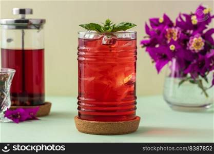 Freshly brewed iced red fruit tea on green table