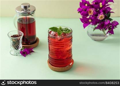 Freshly brewed iced red fruit tea on green table