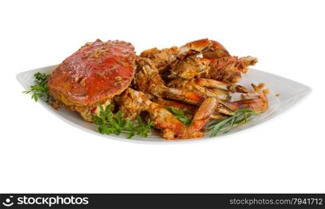 Freshly cooked crab with spicy sauce and herbs on serving plate. Isolated on white background with selective focus towards front.