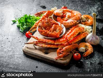 Freshly cooked crayfish, crab and shrimp with herbs. On dark rustic background. Freshly cooked crayfish, crab and shrimp with herbs.