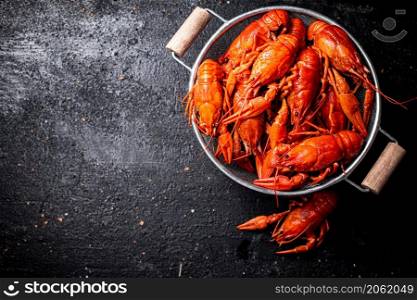 Freshly cooked crayfish in a colander. On a black background. High quality photo. Freshly cooked crayfish in a colander.