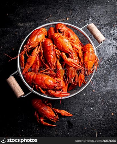 Freshly cooked crayfish in a colander. On a black background. High quality photo. Freshly cooked crayfish in a colander.