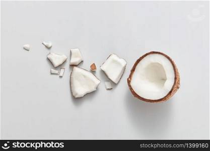 Freshly cut natural organic pieces of natural exotic coconut fruit on a light grey background with soft shadows, copy space. Vegetarian concept. Top view.. Top view of fresh ripe natural organic tropical coconut fruit on a light grey background