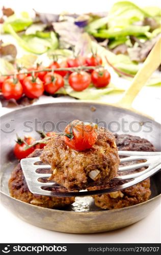 freshly fried meat balls with tomato in a brass pan