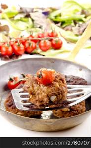 freshly fried meat balls with tomato in a brass pan