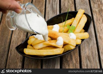 freshly fried potatoes in black plate over wooden old table