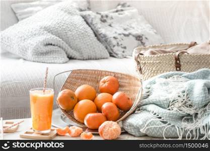 Freshly-grown organic fresh orange juice in the interior of the house, with a turquoise blanket and a basket of fruit. Healthy food. Vitamin C. Freshly-grown organic fresh orange juice in the interior of the house, with a turquoise blanket and a basket of fruit