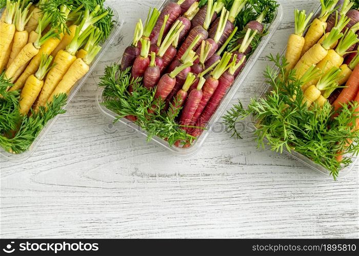 Freshly harvested colorful mini carrots on white wooden background