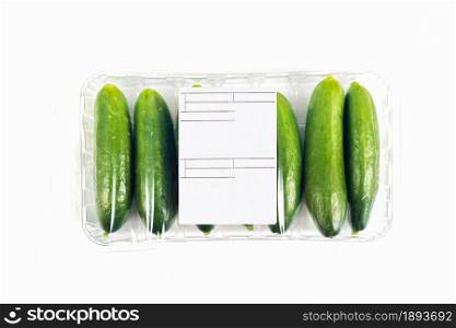 Freshly harvested mini cucumber with package and label on white background