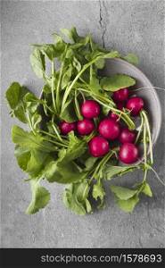Freshly harvested, purple colorful radish in the bowl on gray concrete background. Growing radish. Growing vegetables. Seasonal Cooking, food styling. European red radishes (Raphanus sativus). raw foods concept