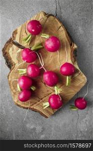 Freshly harvested, purple colorful radish on wooden cutting board. Growing radish. Growing vegetables. Seasonal Cooking, food styling. European red radishes (Raphanus sativus). raw foods concept