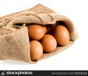 Freshly laid organic eggs in burlap sack isolated. Easter background with brown organic eggs arranged in burlap sack and isolated against white background. Freshly laid organic eggs in burlap sack isolated