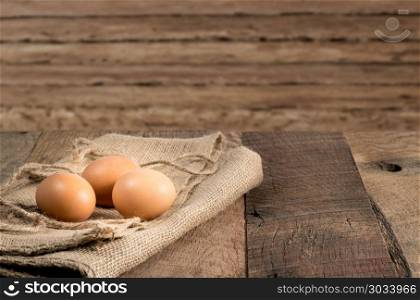 Freshly laid organic eggs on wooden bench. Easter background with brown organic eggs arranged on burlap sack on rustic wooden table. Freshly laid organic eggs on wooden bench