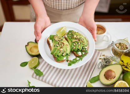 Freshly made Avocado and cream cheese toasts on a white ceramic plate and ingredients.. Freshly made Avocado and cream cheese toasts on a white ceramic plate and ingredients