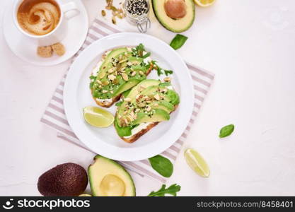 Freshly made Avocado and cream cheese toasts on a white ceramic plate and ingredients.. Freshly made Avocado and cream cheese toasts on a white ceramic plate and ingredients