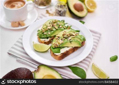 Freshly made Avocado and cream cheese toasts on a white ceramic plate and ingredients.. Freshly made Avocado and cream cheese toasts on a white ceramic plate and ingredients