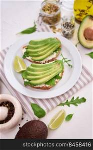 Freshly made Avocado and cream cheese toasts on a white ceramic plate and ingredients.. Freshly made Avocado and cream cheese toasts on a white ceramic plate and ingredients