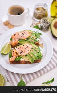 Freshly made Avocado, salmon and cream cheese toasts on a white ceramic plate.. Freshly made Avocado, salmon and cream cheese toasts on a white ceramic plate