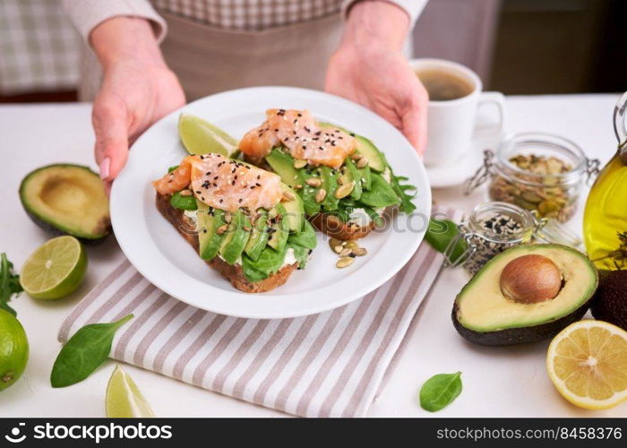 Freshly made Avocado, salmon and cream cheese toasts on a white ceramic plate.. Freshly made Avocado, salmon and cream cheese toasts on a white ceramic plate