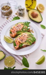 Freshly made Avocado, salmon and cream cheese toasts on a white ceramic plate.. Freshly made Avocado, salmon and cream cheese toasts on a white ceramic plate