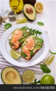 Freshly made Avocado, salmon and cream cheese toasts on a white ceramic plate.. Freshly made Avocado, salmon and cream cheese toasts on a white ceramic plate