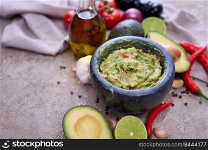 freshly made guacamole in marble mortar with ingredients on grey concrete background.. freshly made guacamole in marble mortar with ingredients on grey concrete background