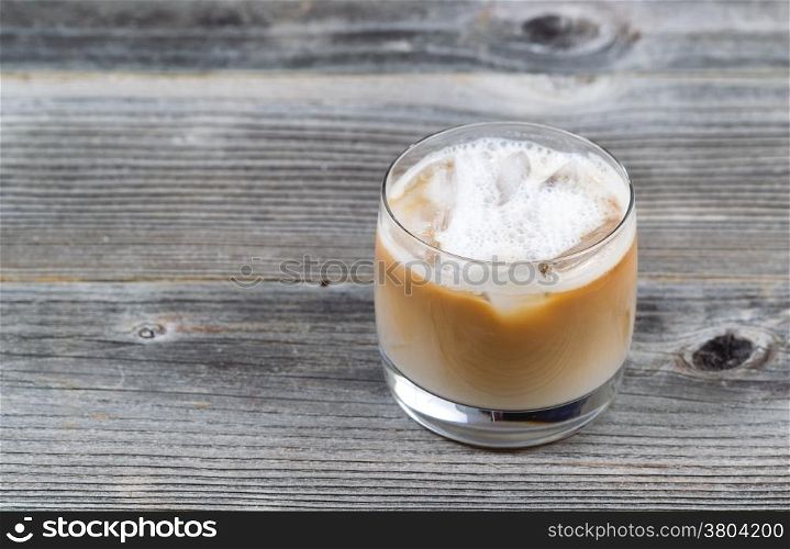 Freshly made Iced Coffee with cream in glass on rustic wood