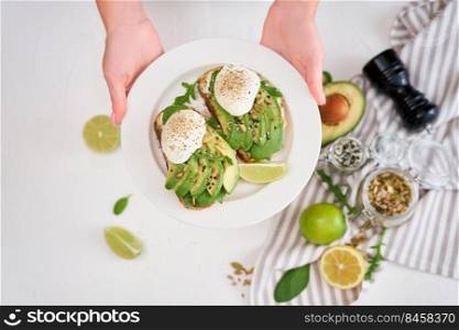 Freshly made poached egg and Avocado toasts on light grey background.. Freshly made poached egg and Avocado toasts on light grey background