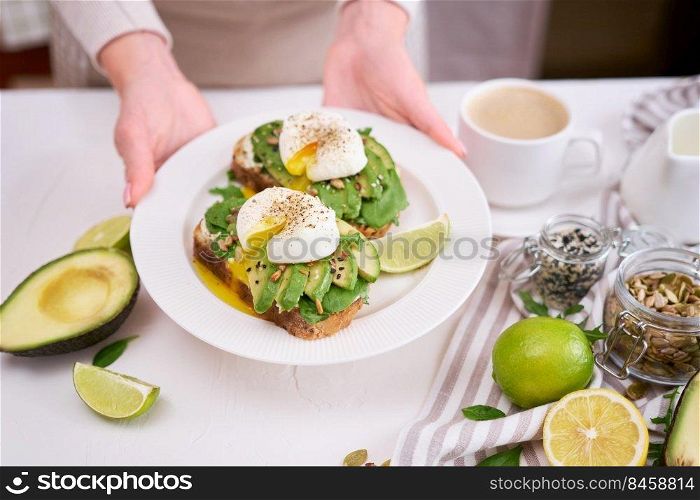 Freshly made poached egg and Avocado toasts on light grey background.. Freshly made poached egg and Avocado toasts on light grey background