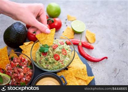 freshly made salsa and guacamole dip sauce with nacho chips on stone serving board.. freshly made salsa and guacamole dip sauce with nacho chips on stone serving board