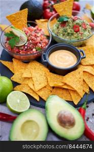 freshly made salsa and guacamole dip sauce with nacho chips on stone serving board.. freshly made salsa and guacamole dip sauce with nacho chips on stone serving board