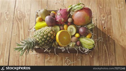 Freshly picked exotic fruits in a box on a wooden background. Top view with movement of daylight above the box. Motion, 4K UHD video, 3840, 2160p.. The motion of sunlight above the wooden box with fresh natural organic tropical fruits on a wooden table. Motion, 4K UHD video, 3840, 2160p.