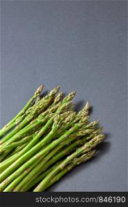 Freshly picked raw natural asparagus for preparation vegan food on a grey background with copy space. Vegetarian healthy eating.. Pile of green organic asparagus on a grey background.