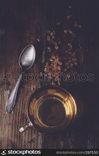 freshly poured tea with brown tea sugar on a wooden background